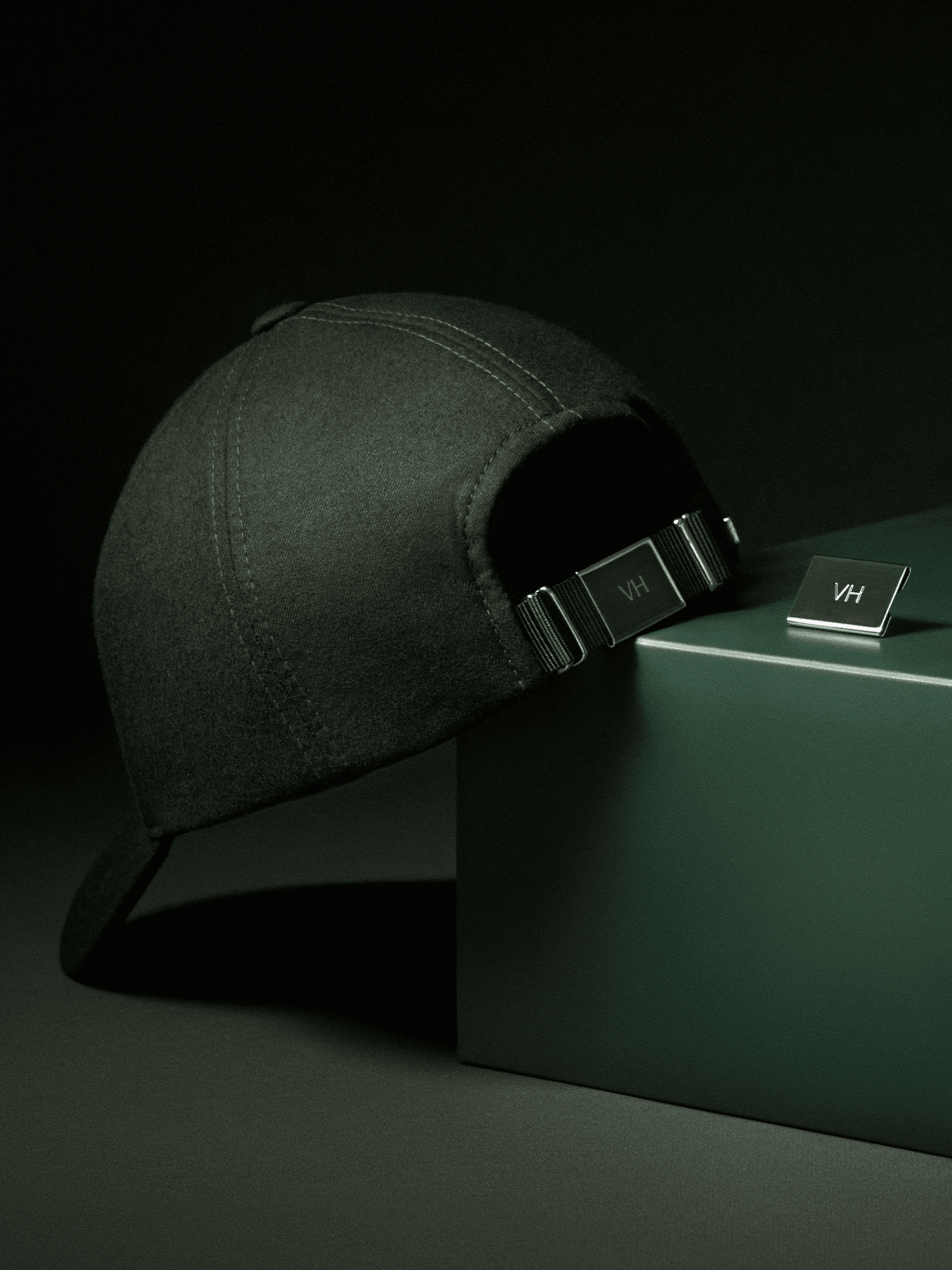 Back view of dark green wool cap with personalized engraving plate on back strap