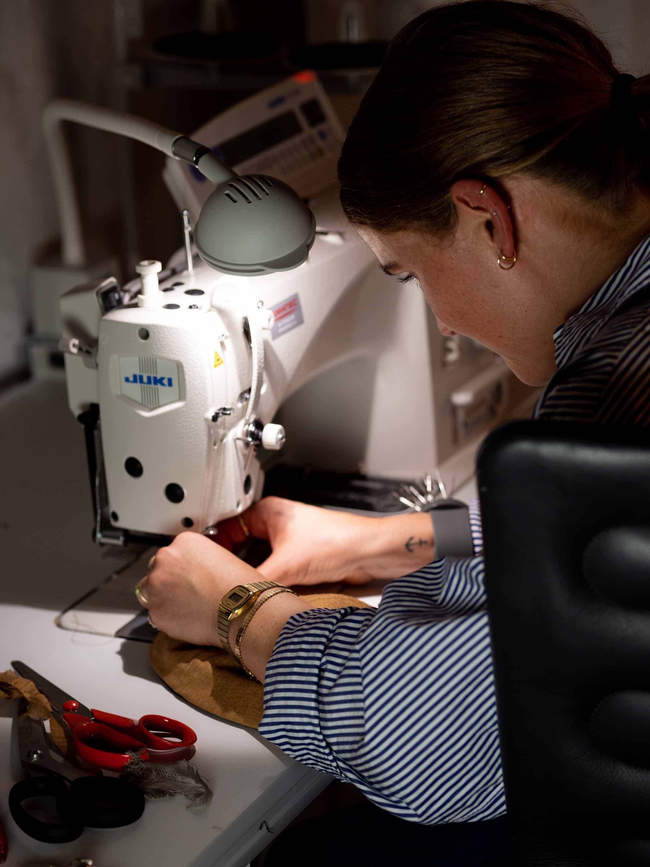 Behind the scenes image of designer working on sewing machine