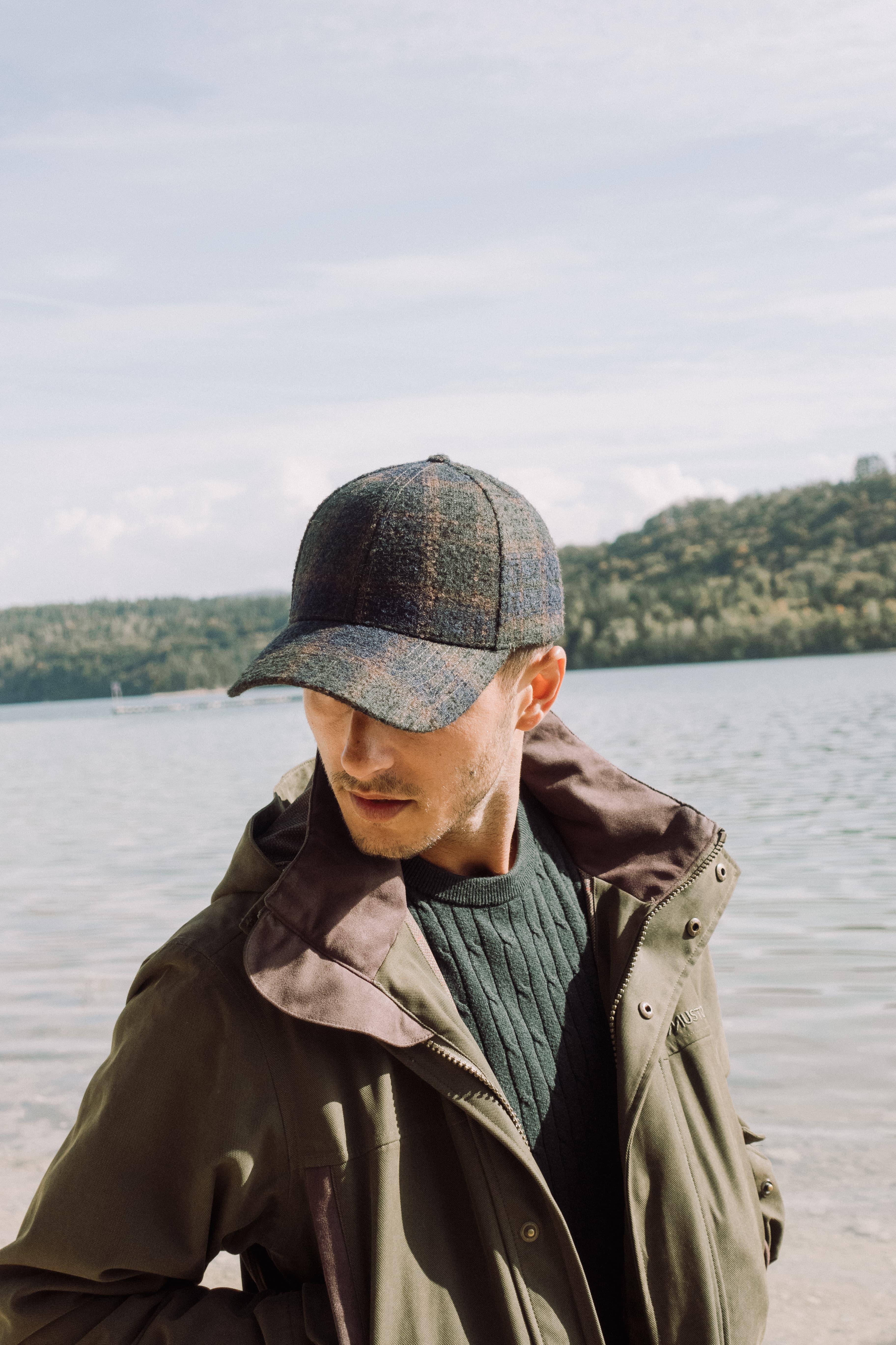 Front image of male model wearing alpaca wool cap in green check