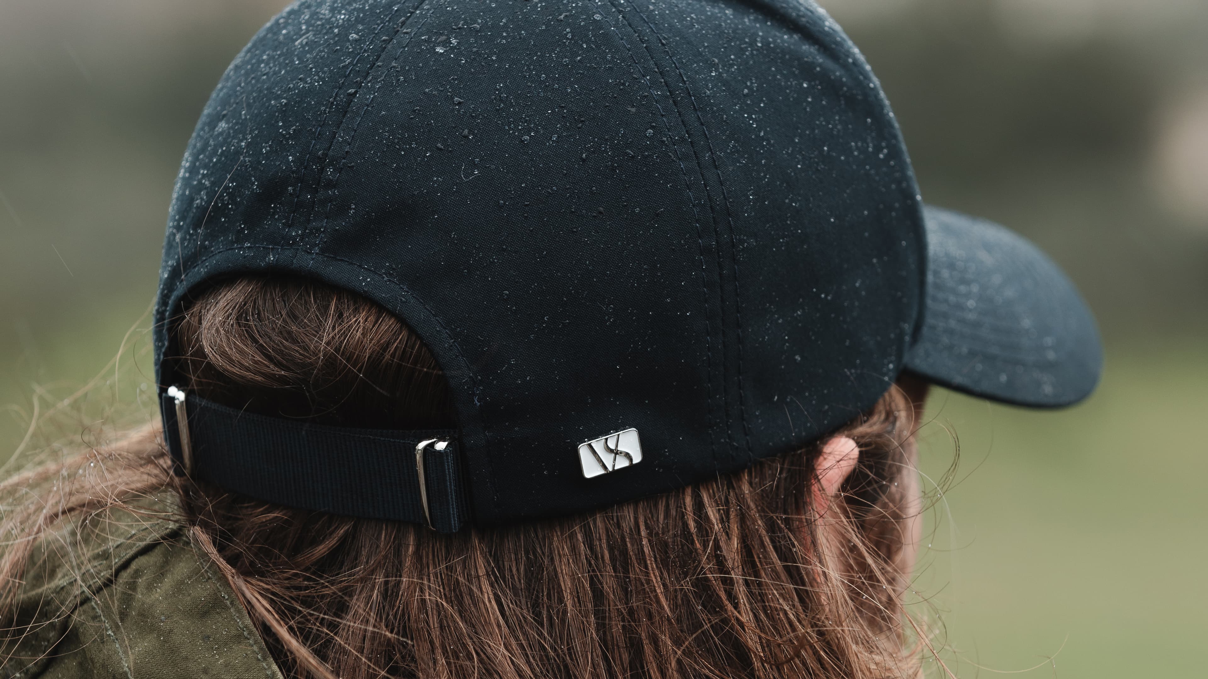 Back view of a black varsity headwear cap in rain