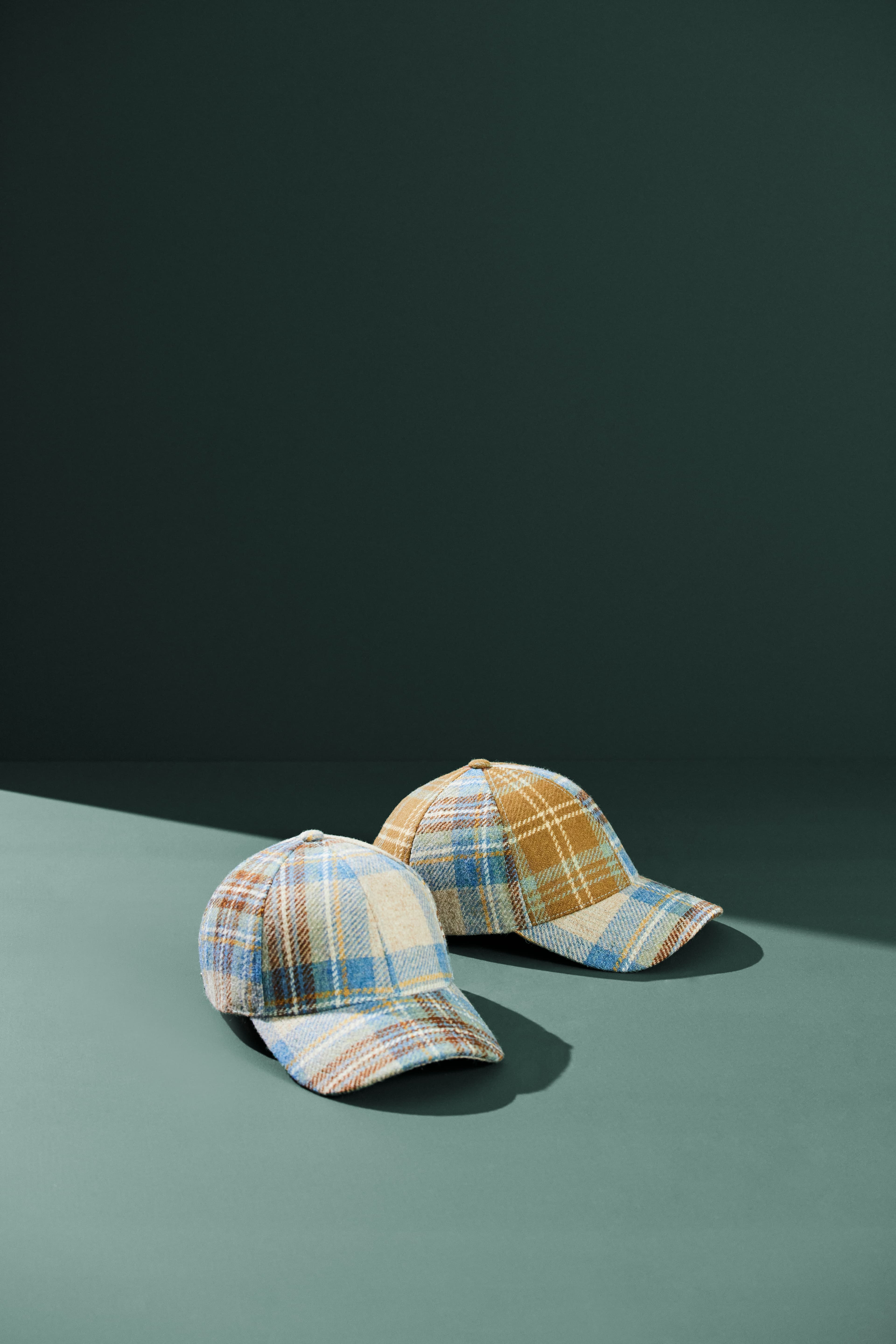 Front and side view of tartan wool caps for varsity vault with green background