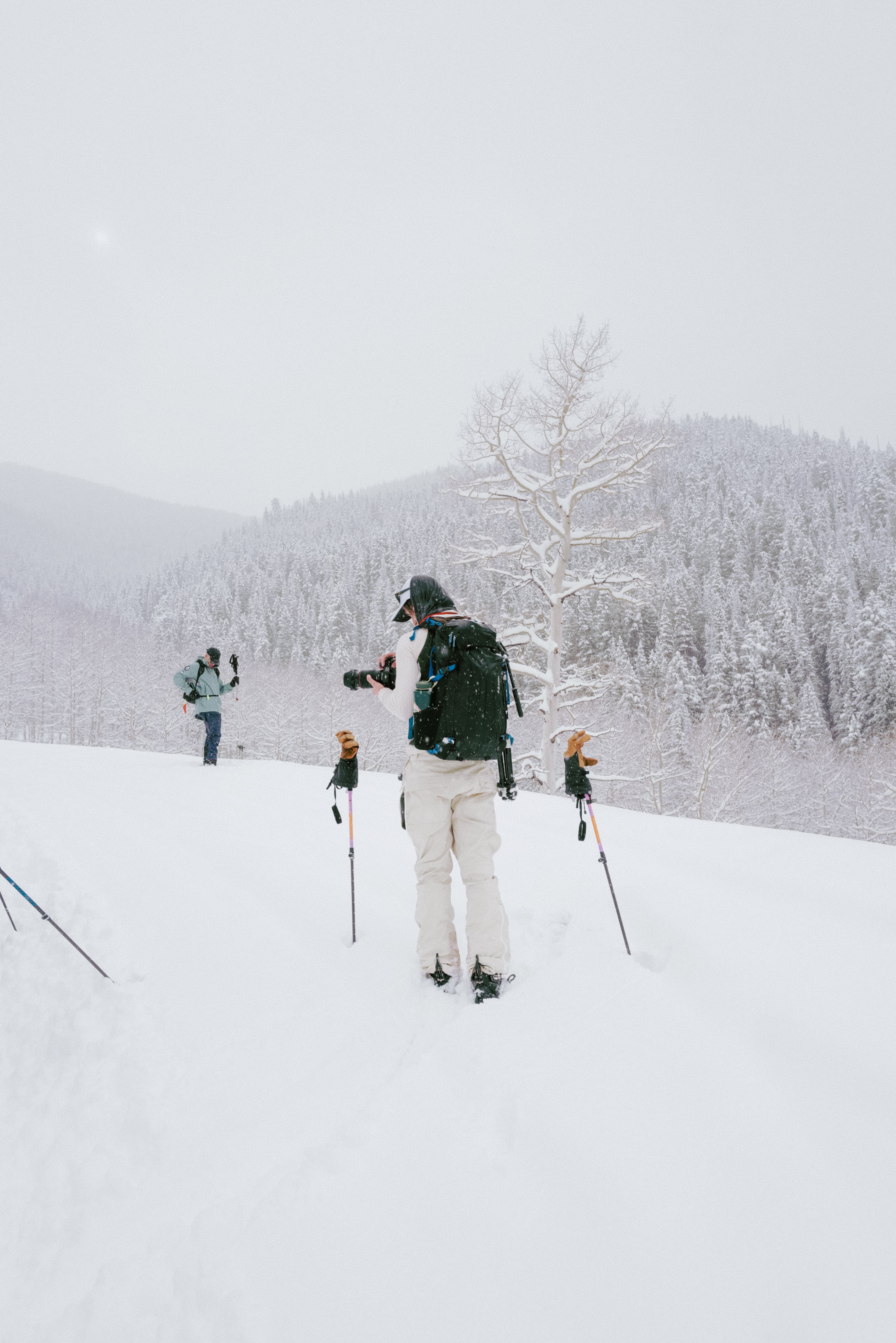 Back view of photographer in snowy conditions on skiis