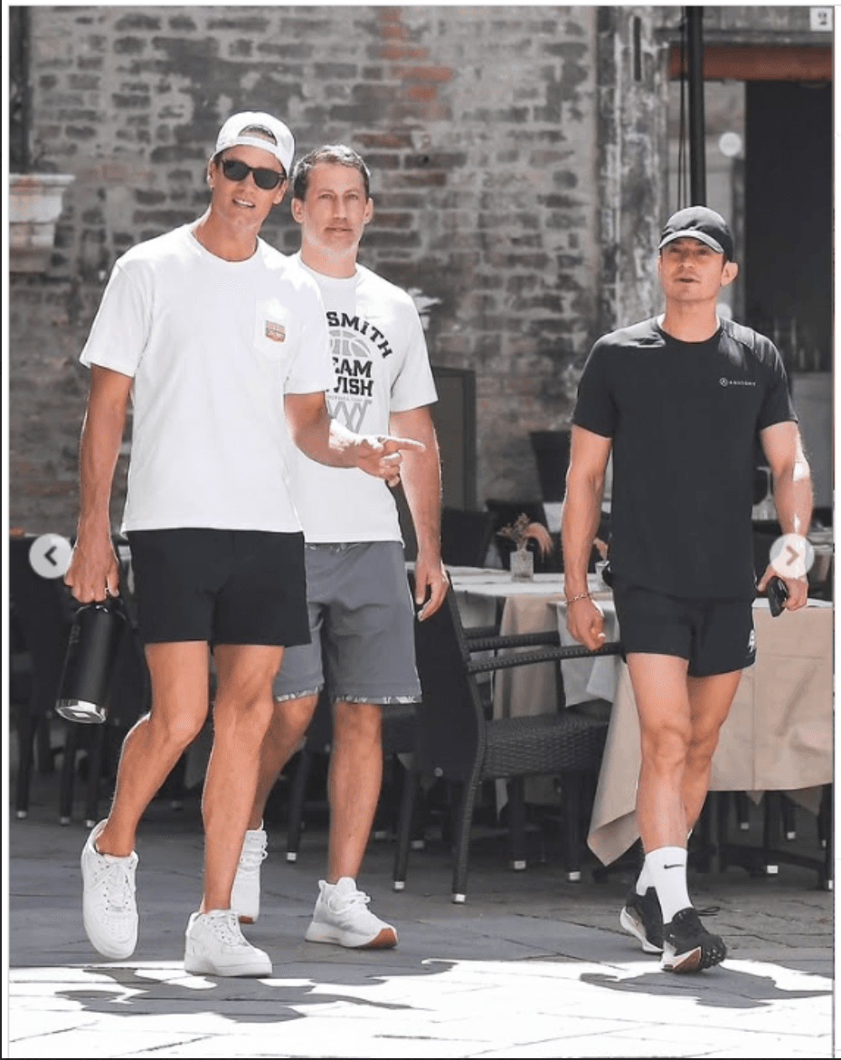 Tom Brady and Orlando Bloom wearing caps before the Bezos–Sánchez Wedding