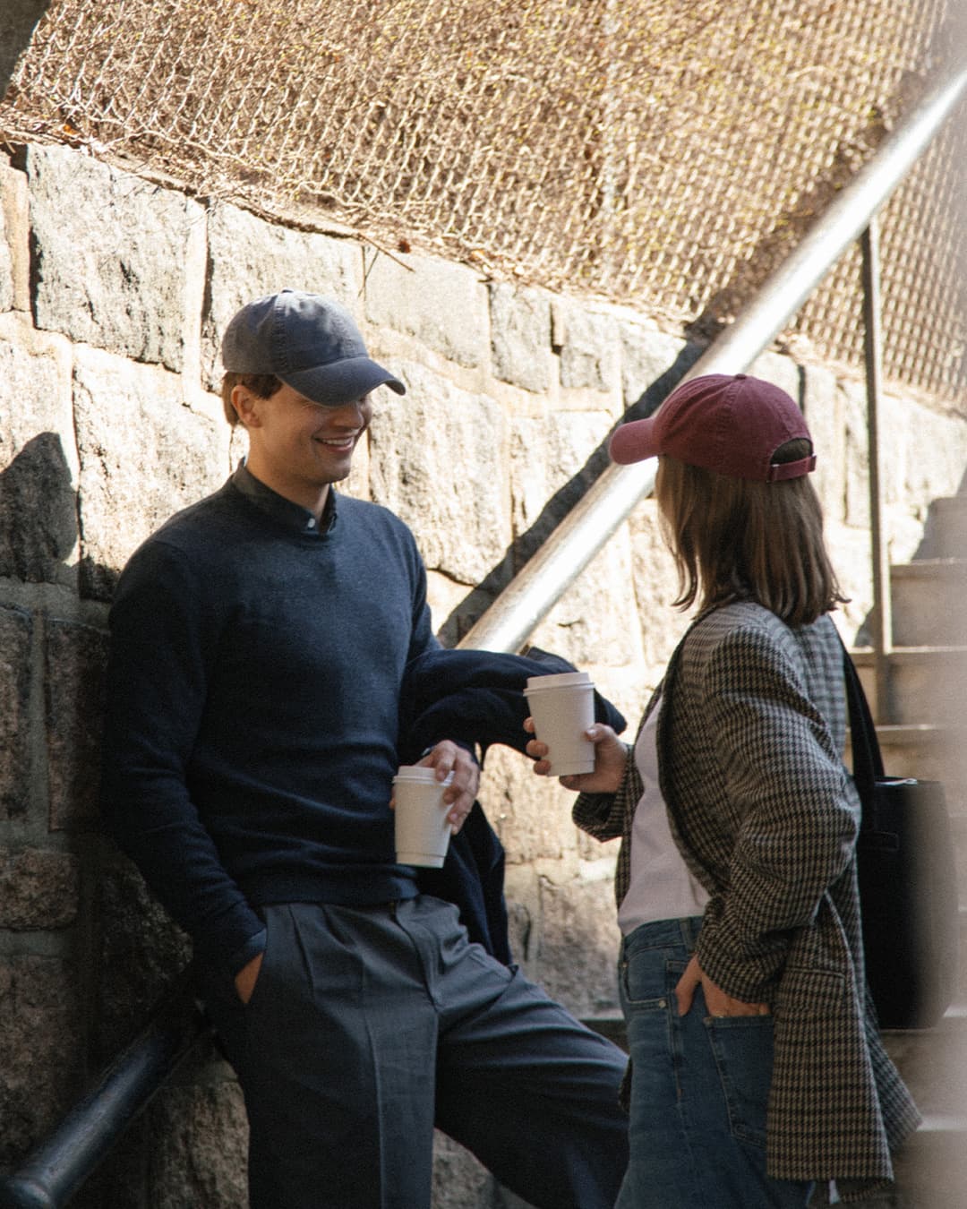 Side view of male and female wearing washed cotton caps while drinking coffe
