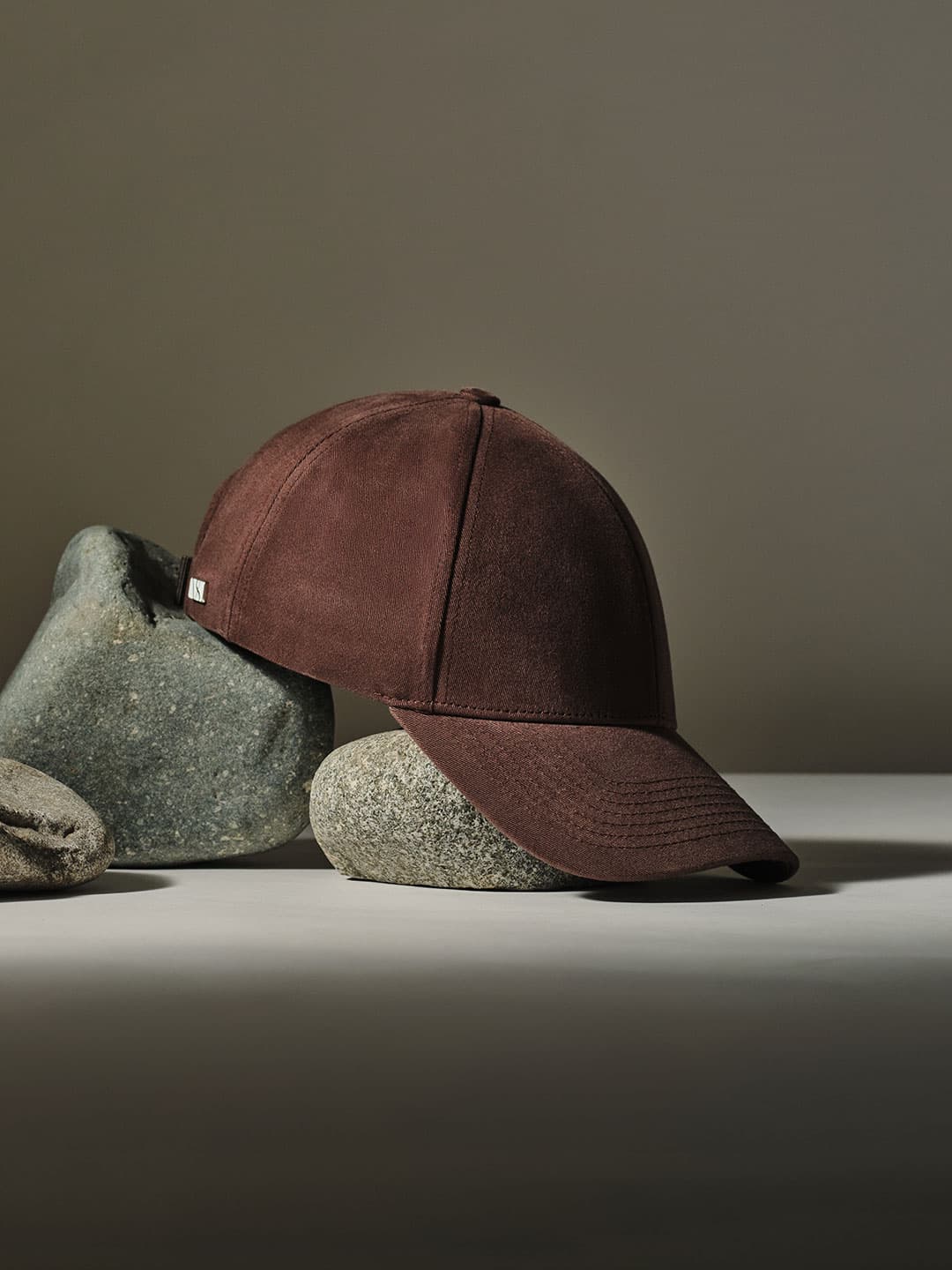 A brown cap displayed on smooth gray stones against a neutral background.