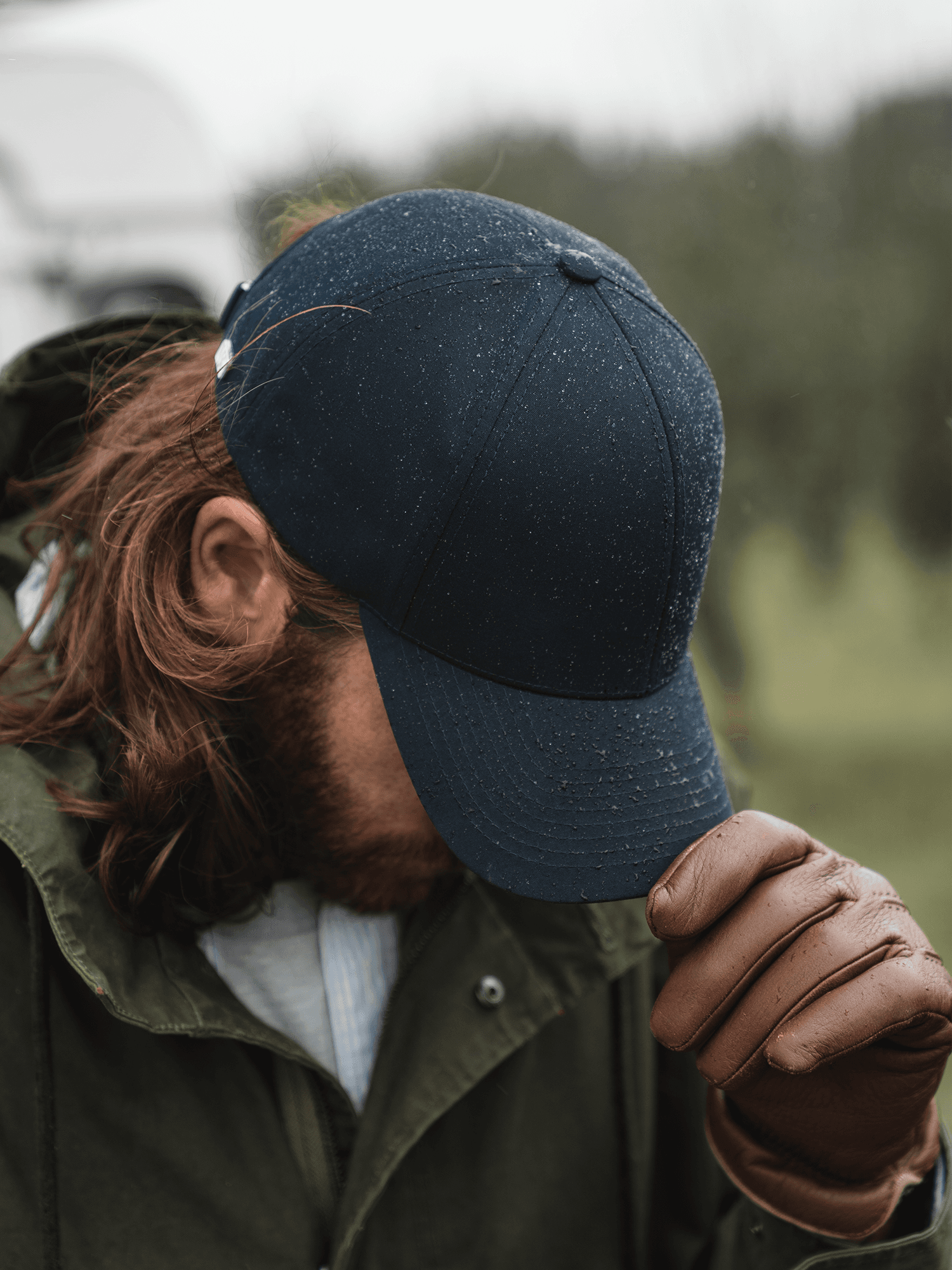 Side view of male model wearing a dark navy ventile cotton cap in rainy weather