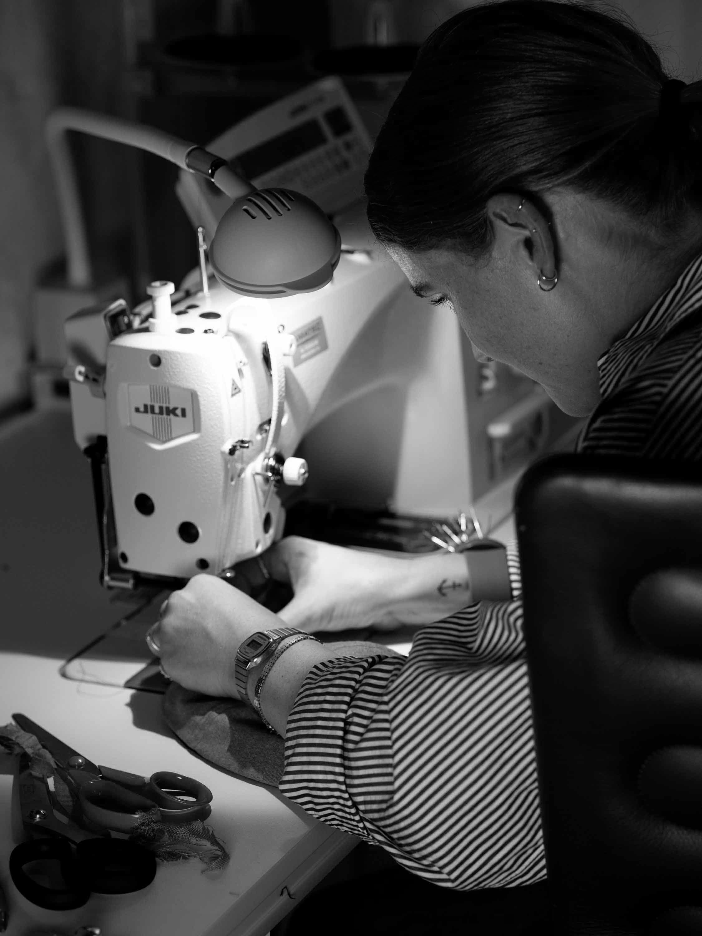 Behind the scenes image of varsity headwear designer working on sewing machine