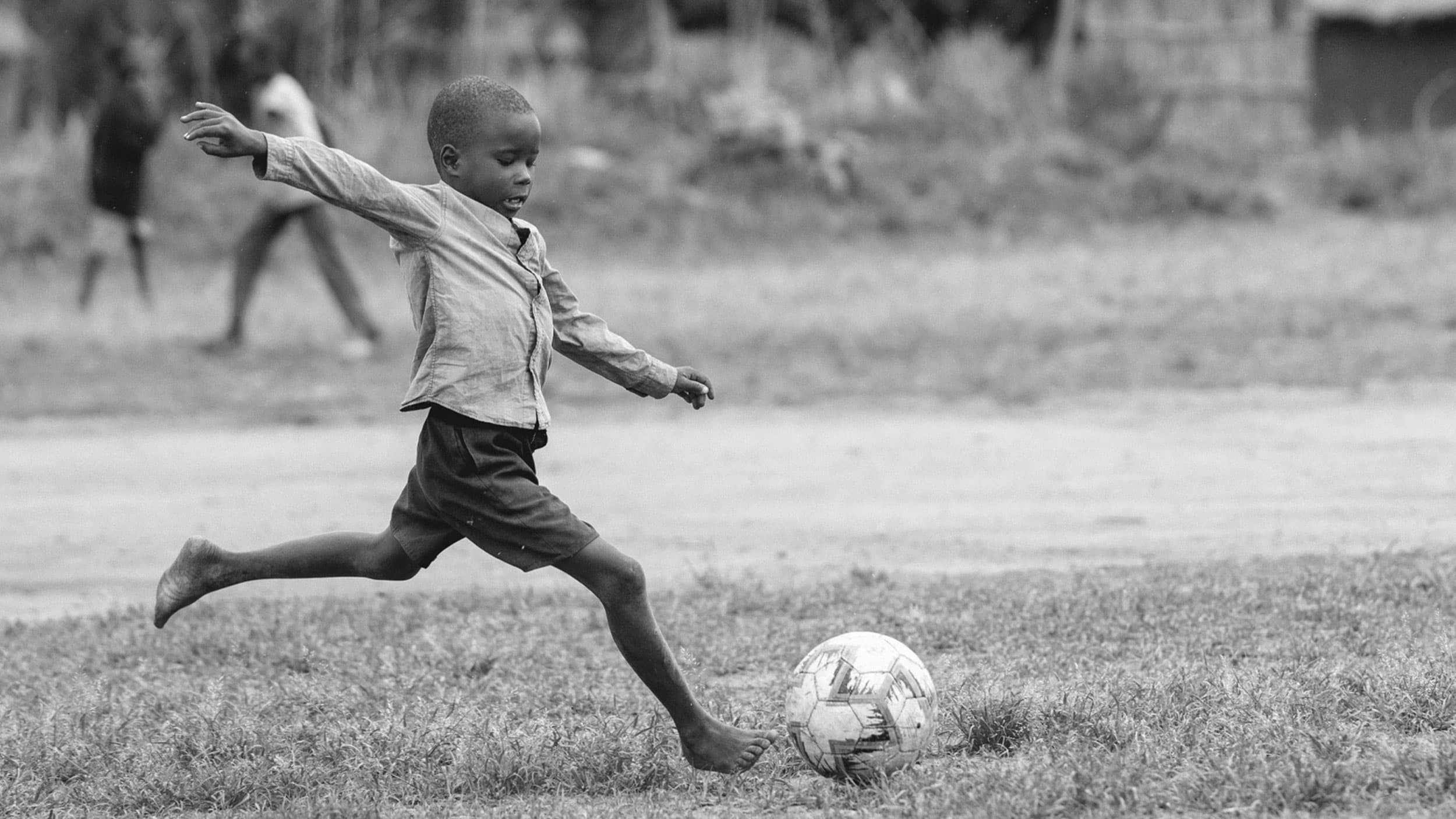 Black and white image of boy playing football