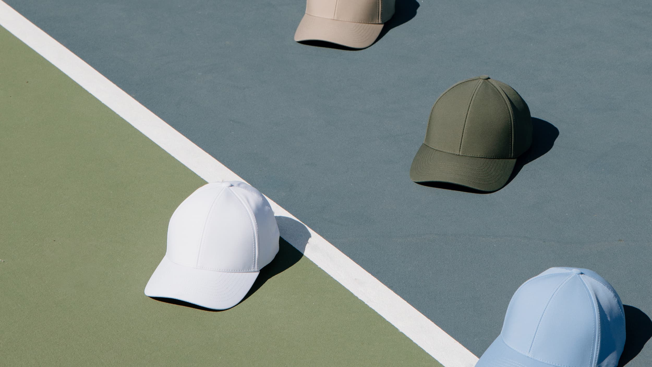 Sport collection from varsity headwear displayed in different colors on tennis court