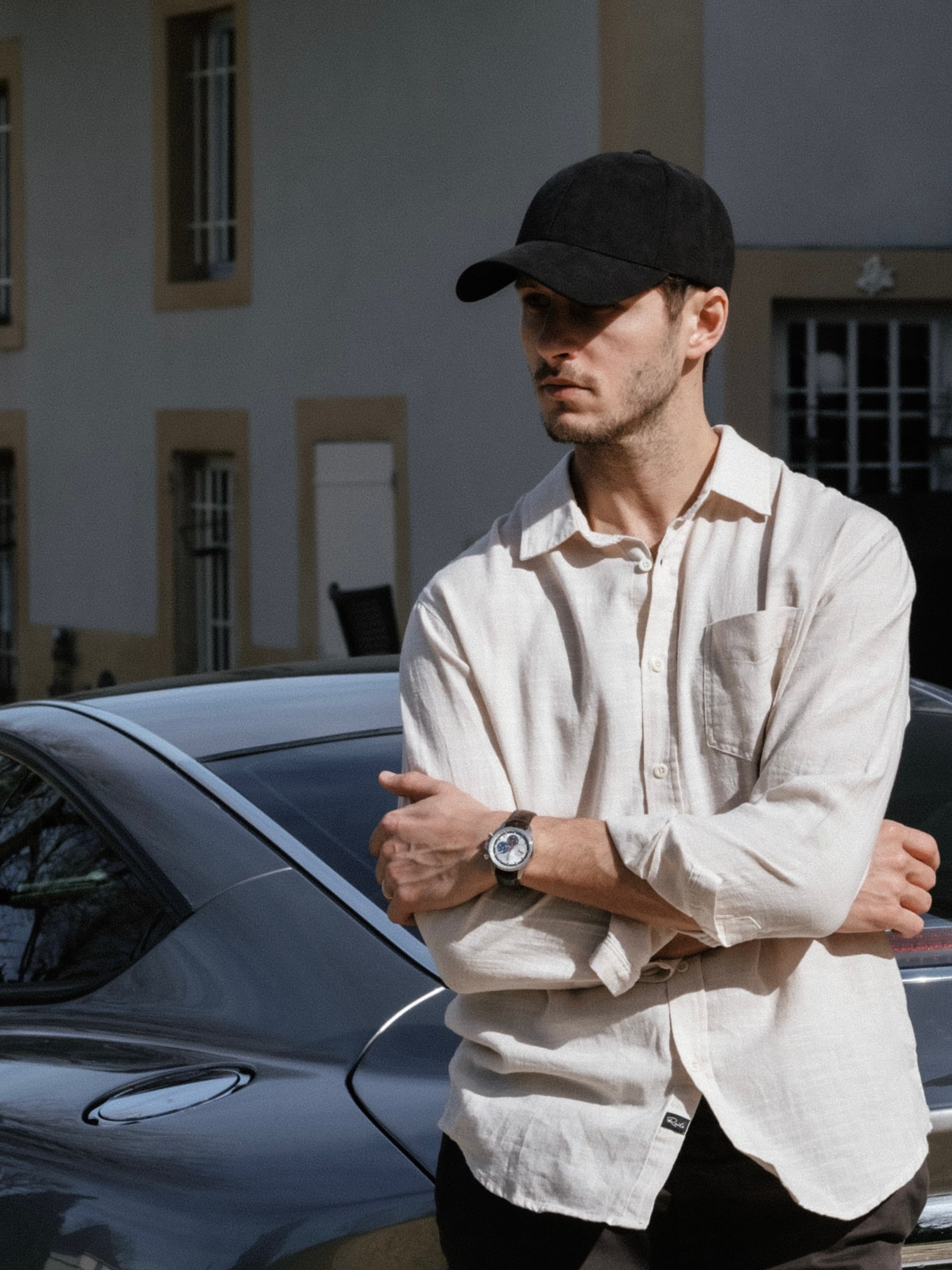 Front view of male wearing alcantara notte black cap in front of car