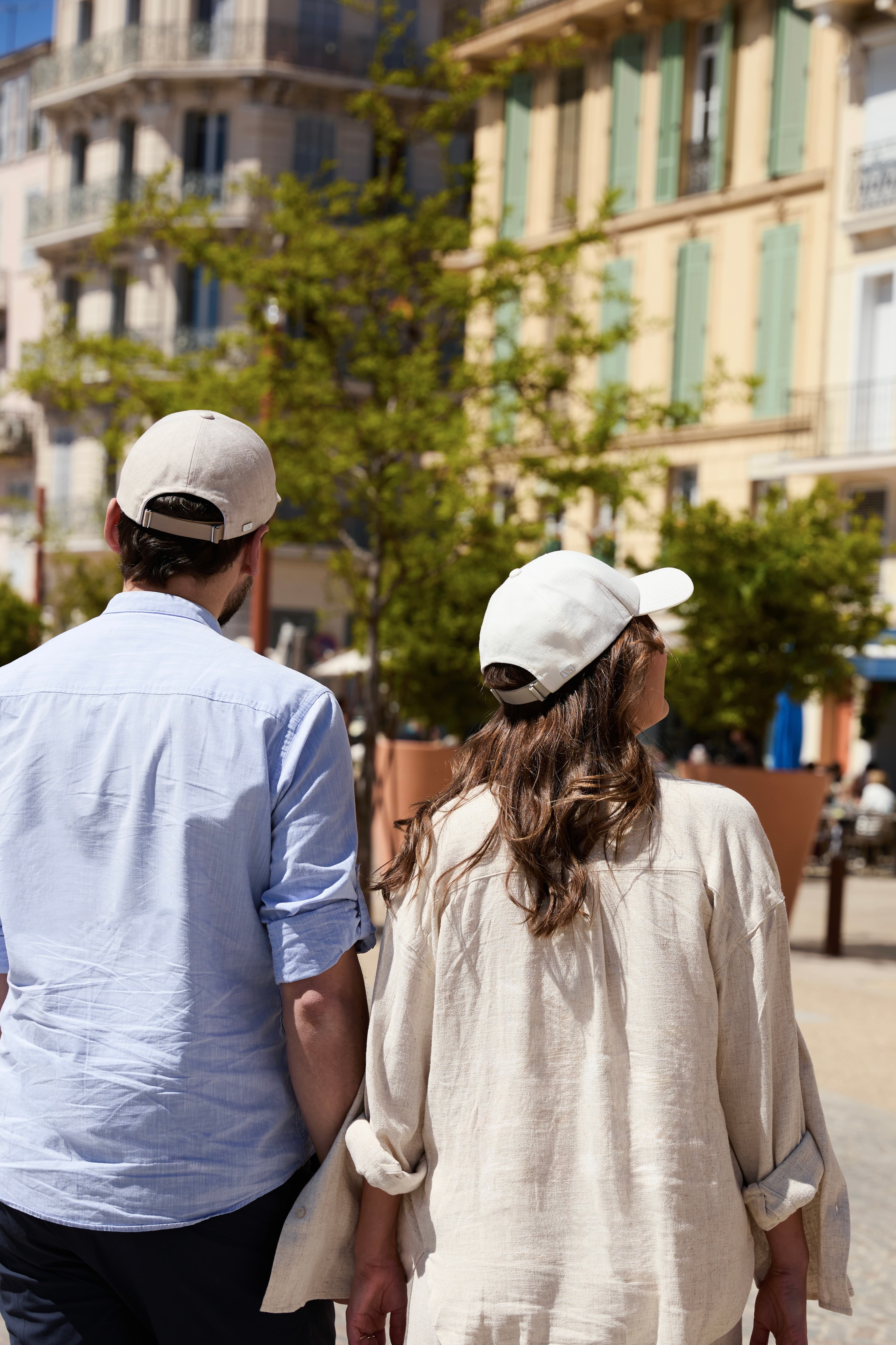 Back view of man and women wearing caps strolling the streets of Cannes