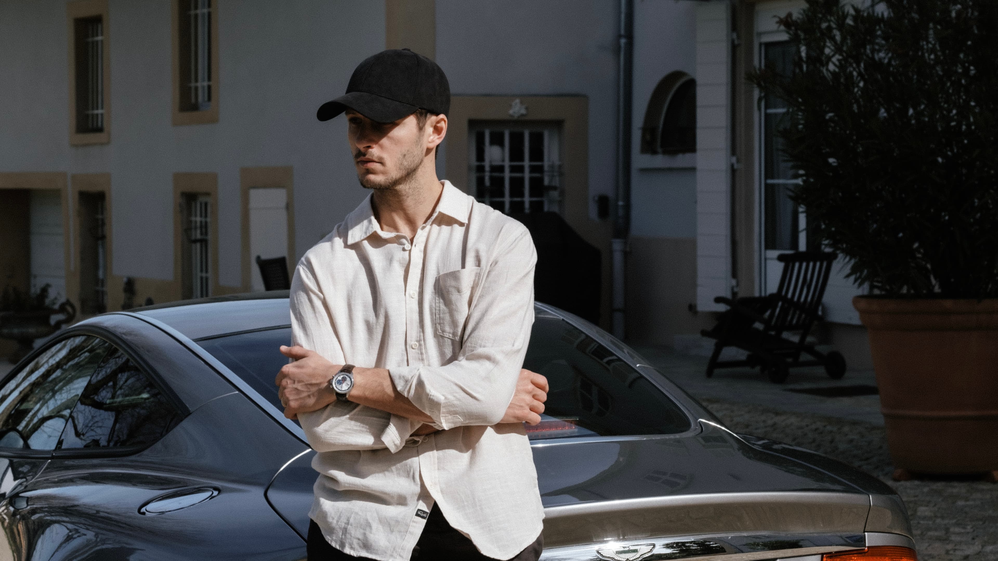 Front view of male wearing alcantara notte black cap in front of car