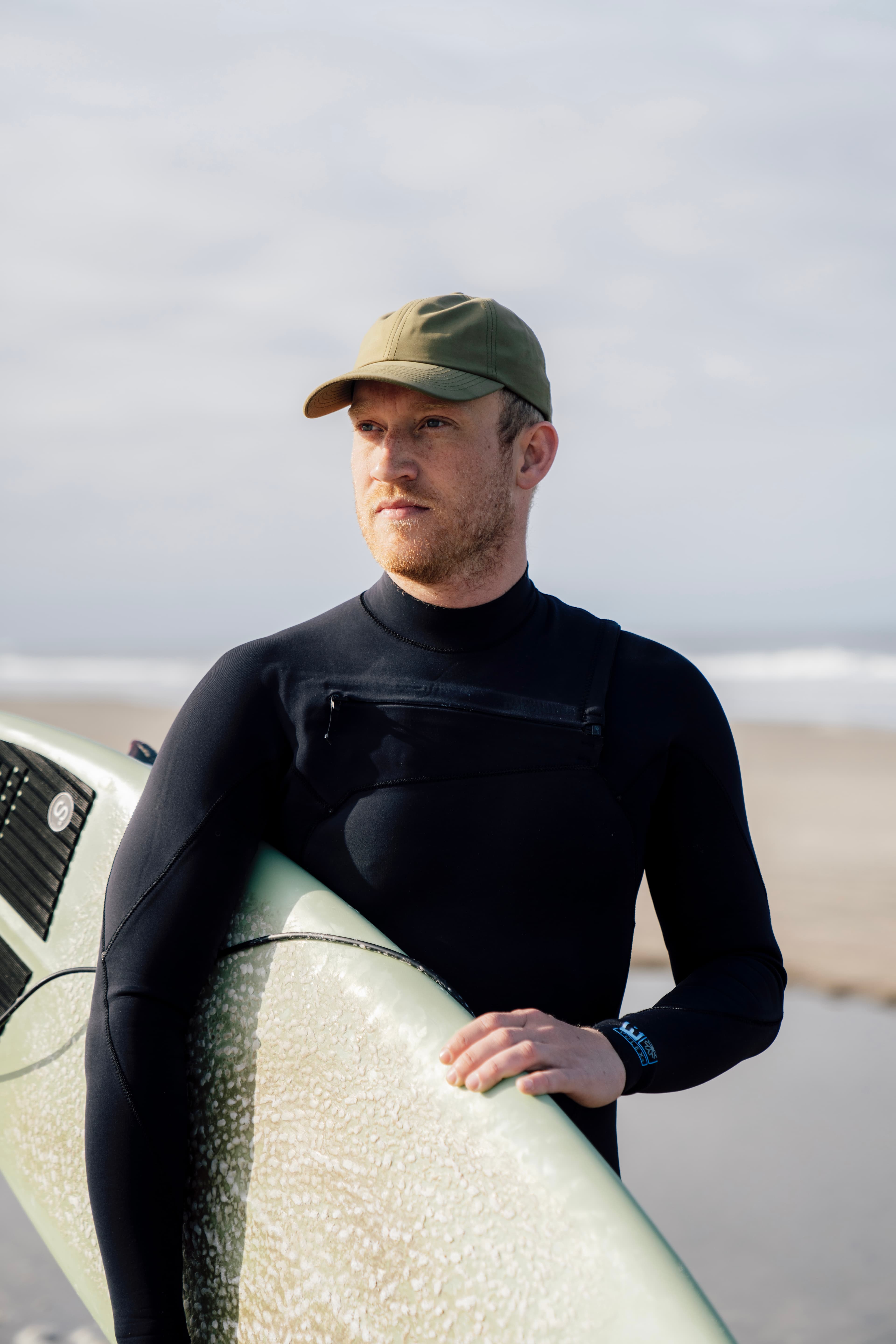 Male wearing seaqual cap at the beach with surf board
