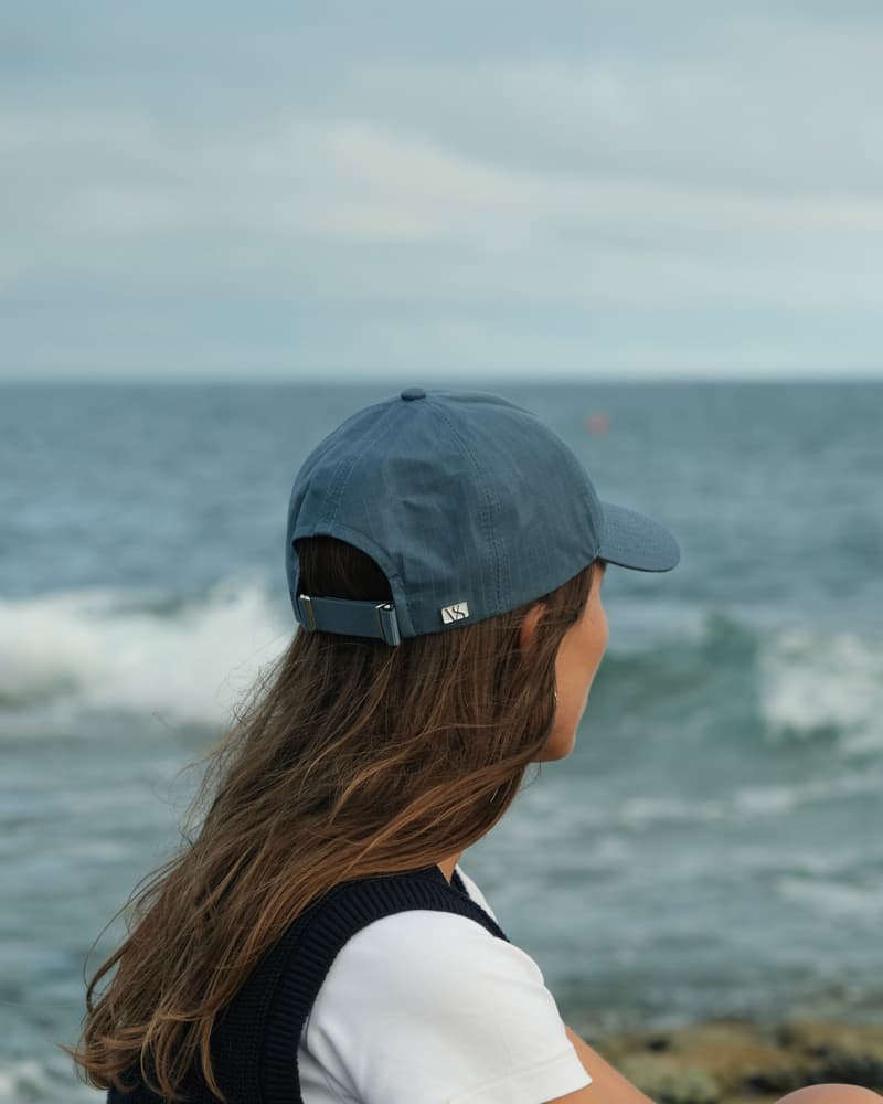 Side view of female model wearing legacy soft oilskin cap by the ocean