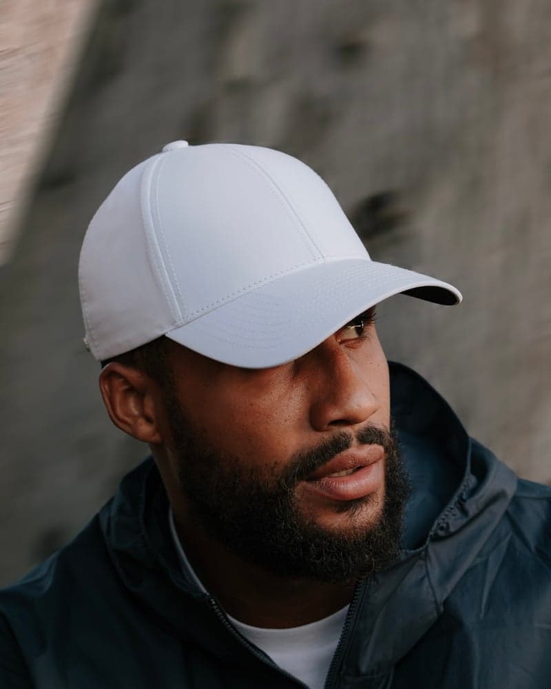 Side view of male model wearing a white legacy structured athletic sport cap