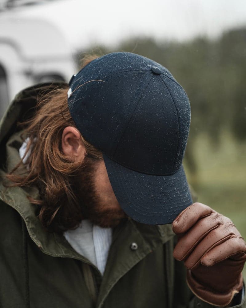 Side view of male model wearing a legacy structured ventile cotton cap in rainy weather
